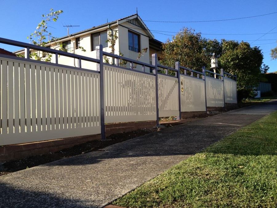 Pale aluminium slat fence with dark posts along a street front
