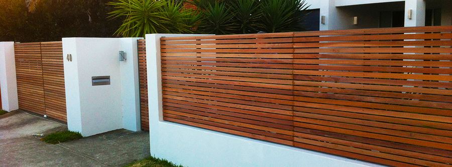 Horizontal timber slat fence and gate between white rendered pillars