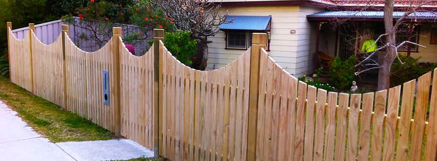 Scalloped timber paling fence along a street front