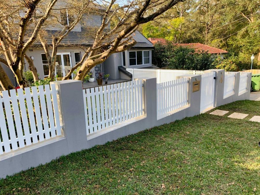 White picket fence and gate between rendered pillars